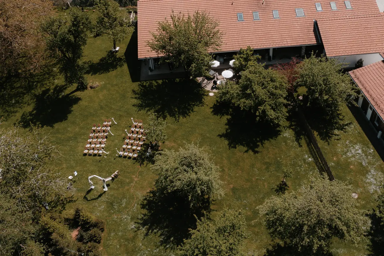 Luftaufnahme einer freien Trauung mit bestuhlter Zeremonie und Traubogen im Garten des Hof Nr. 6