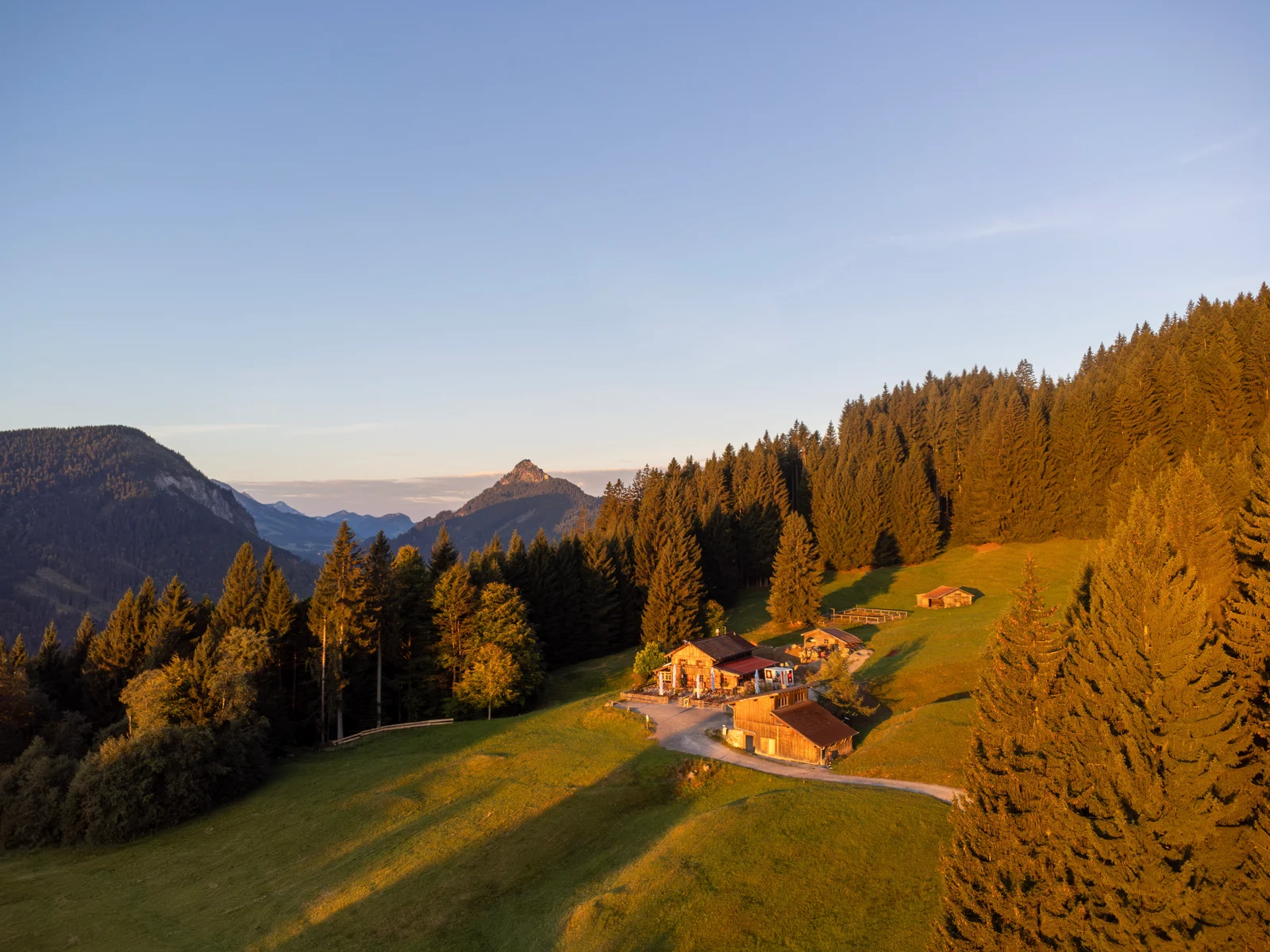 Luftaufnahme der Edelsberghütte auf einer Bergwiese im Abendlicht mit Allgäuer Bergpanorama