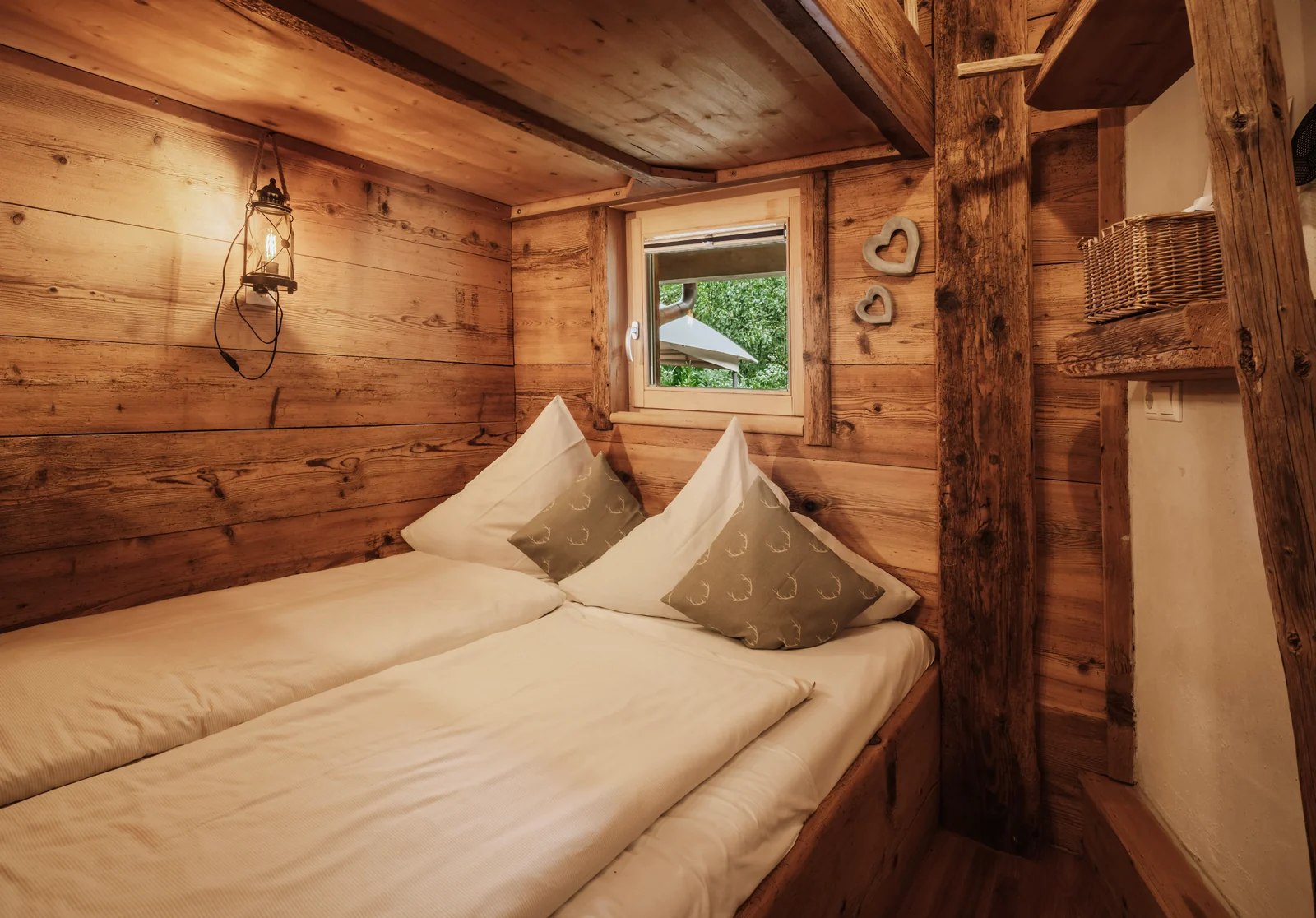 Doppelbett im holzvertäfelten Schlafbereich eines Apartment-Chalets auf der Edelsberghütte