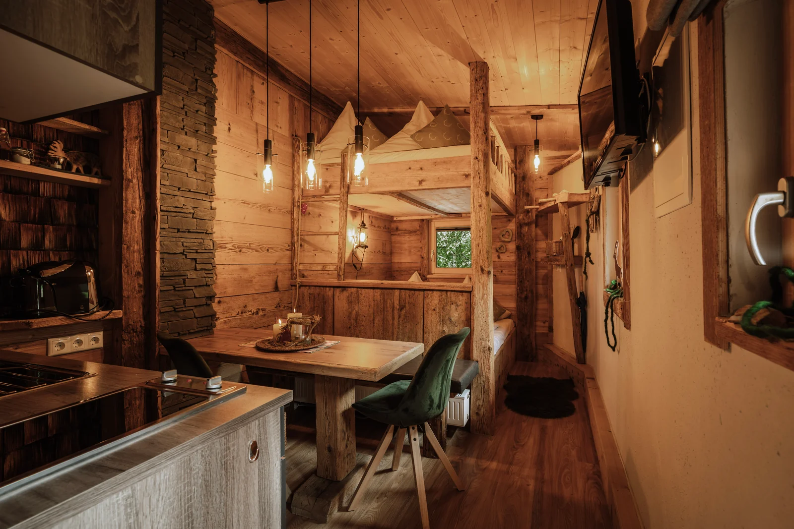 Wohnraum eines Apartment-Chalets auf der Edelsberghütte mit Küchenzeile, Essplatz und Hochbett in Altholz